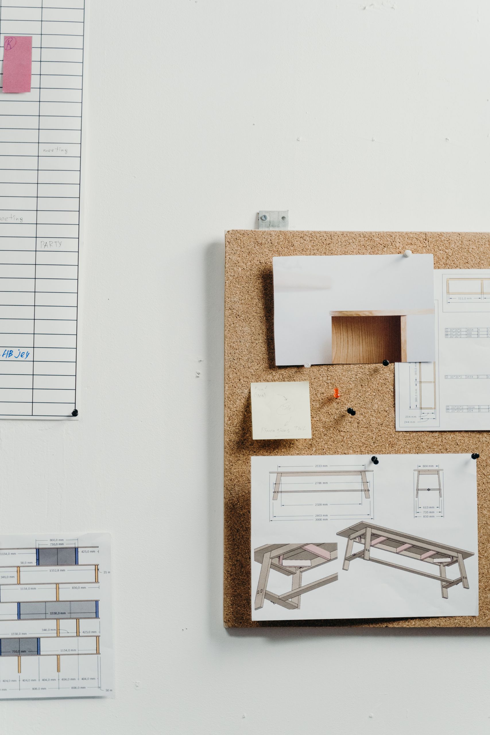 Corkboard displaying architectural drawings in a minimalist office setting.